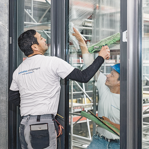 zwei Männer, einer von aussen einer von innen, am Fenserreinigen